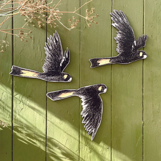 Three metal bird sculptures on a green wooden background