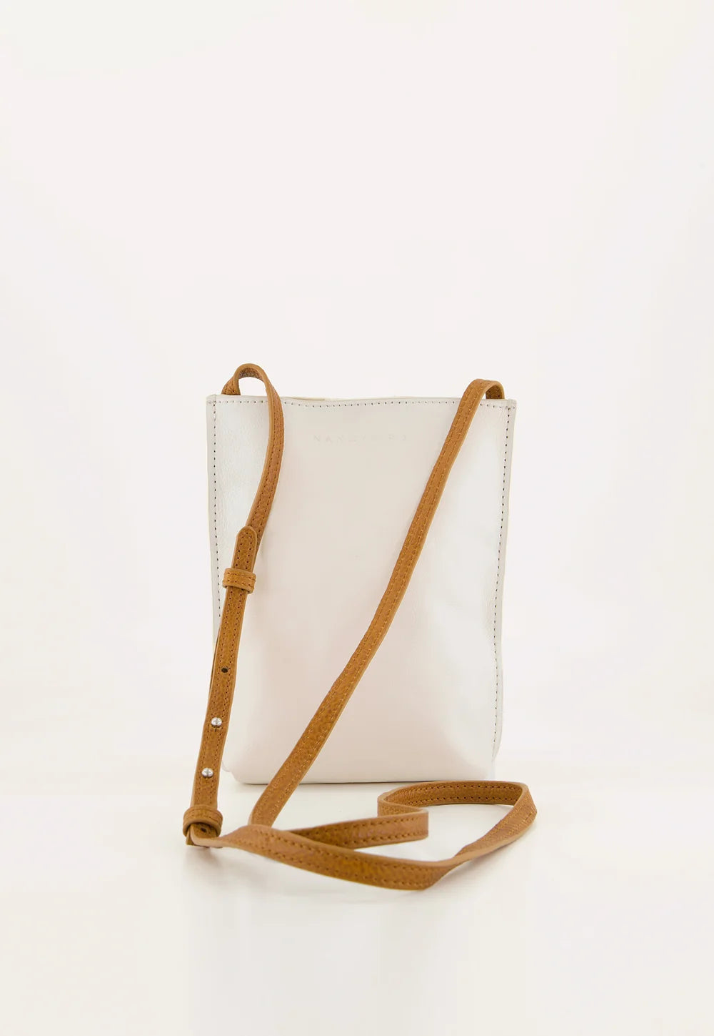White crossbody bag with a brown strap on a white background