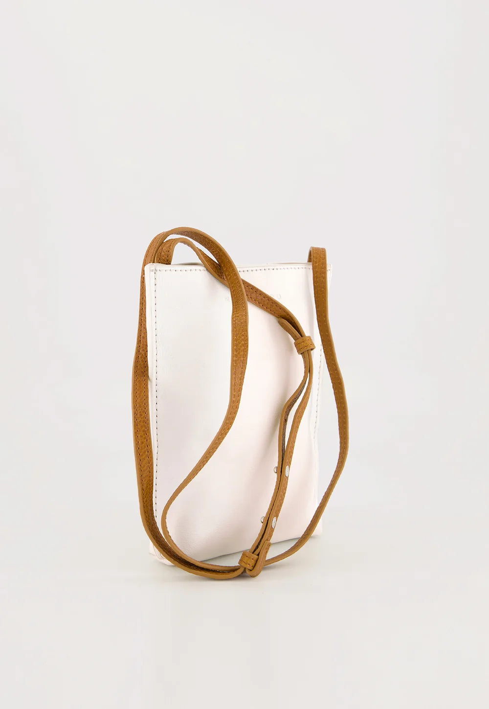 A white leather crossbody bag with a slim adjustable tan leather strap, shown on a clean white background.