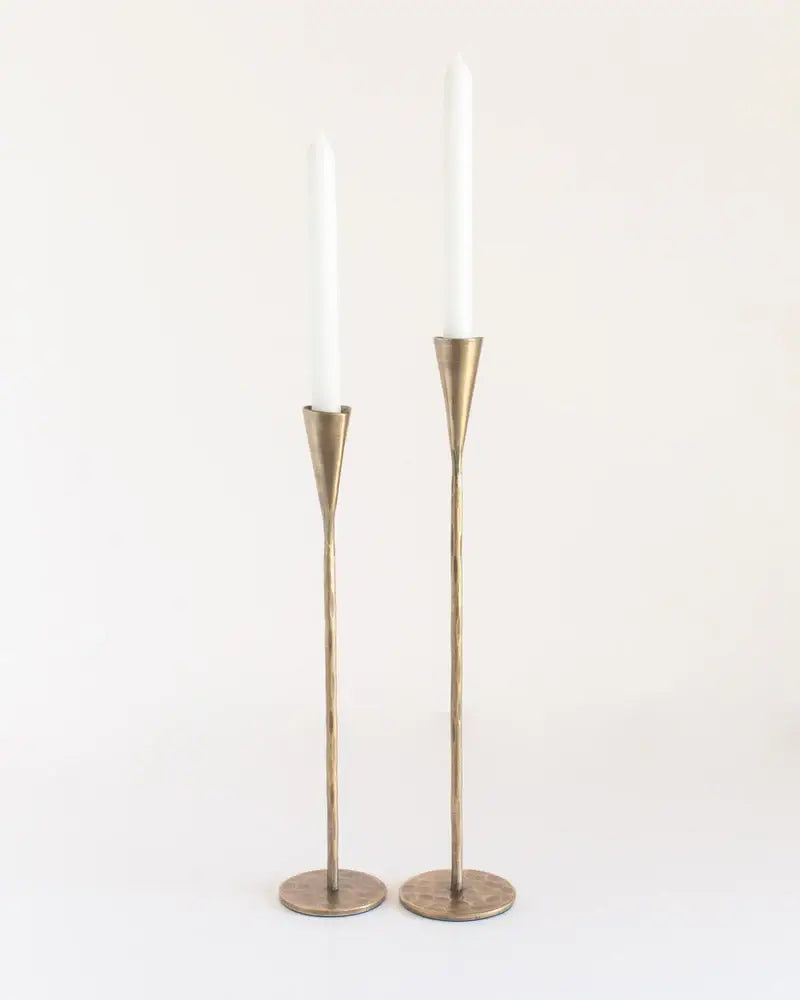 Two brass candle holders with white candles on a white background