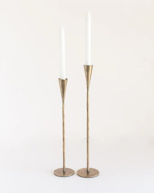 Two brass candle holders with white candles on a white background