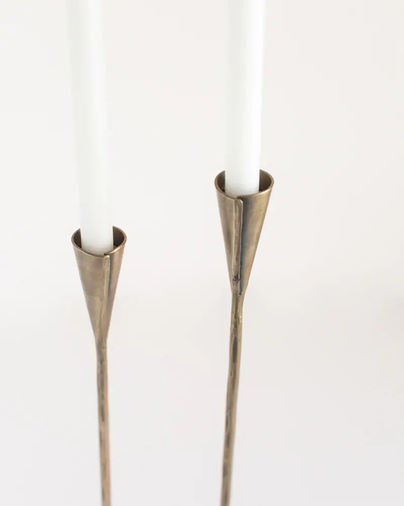 Two metallic candle holders with candles on a white background